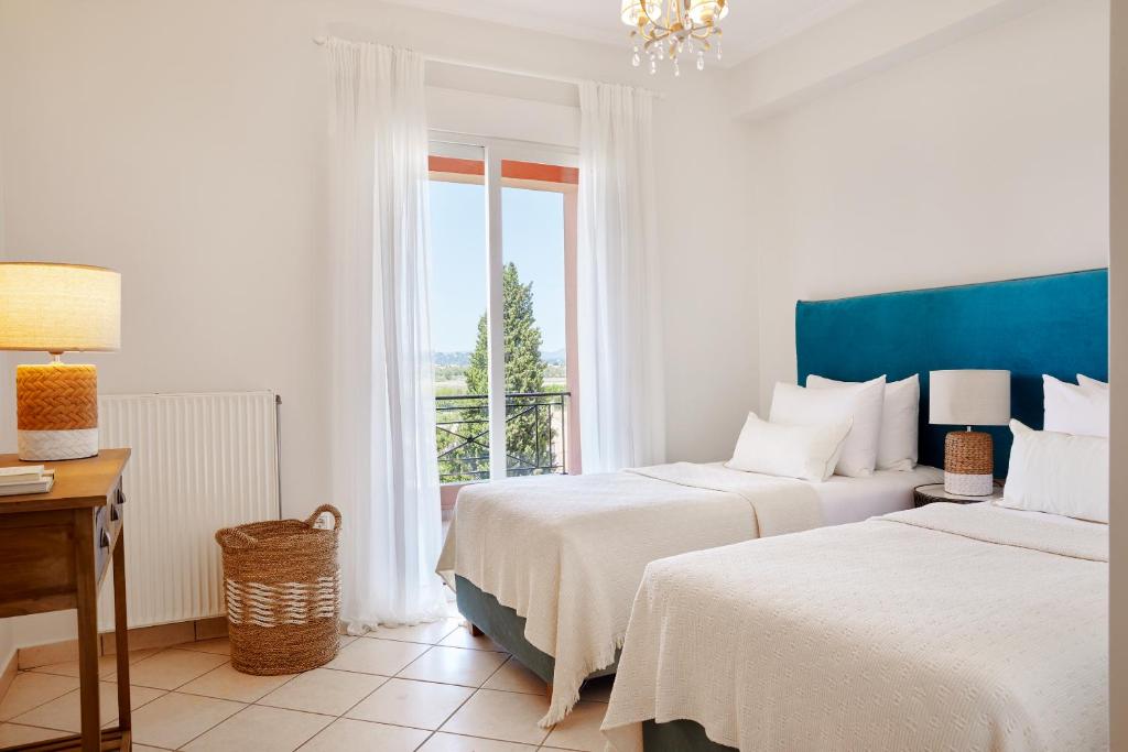 a white bedroom with two beds and a window at Old Town Luxury Suites 'Madame' in Kanoni