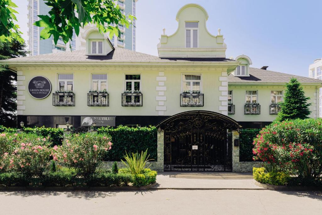 a large white building with a gate and flowers at GREEN HOUSE Detox & SPA Hotel in Sochi