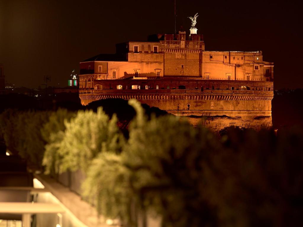 um edifício com uma estátua em cima à noite em Trianon Borgo Pio Aparthotel em Roma