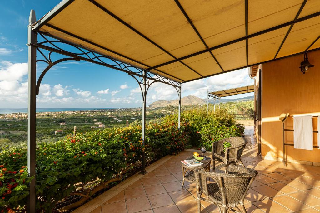 patio con tavolo e sedie sotto un pergolato di Solemar Sicilia - Le Casette Di Calzata a Campofelice di Roccella