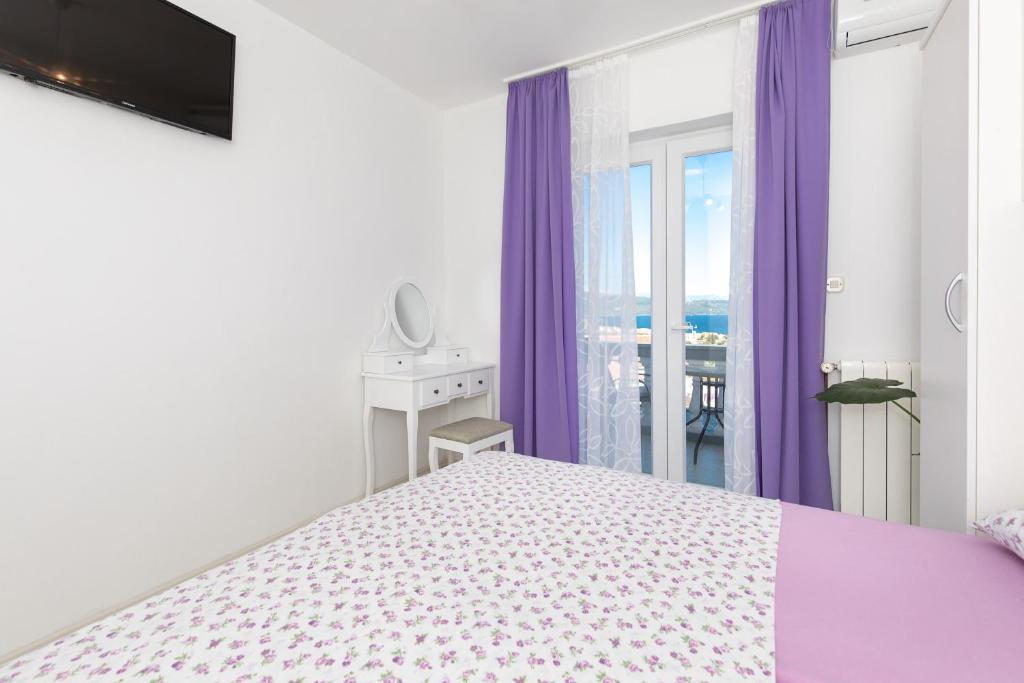 a white bedroom with purple curtains and a bed at Apartment & rooms Ivica in Krk