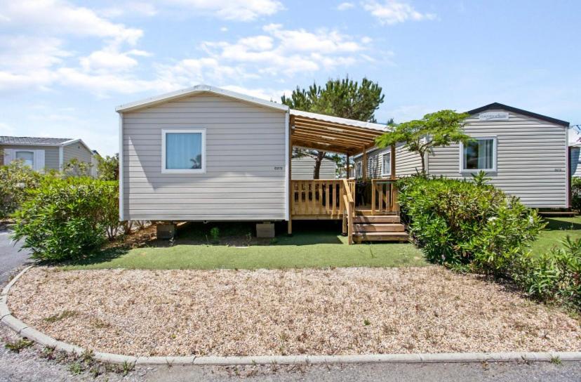 une petite maison avec une terrasse couverte et une terrasse dans l'établissement Particulier loue ce mobil-home 3 chambres, tout confort, à Valras-Plage