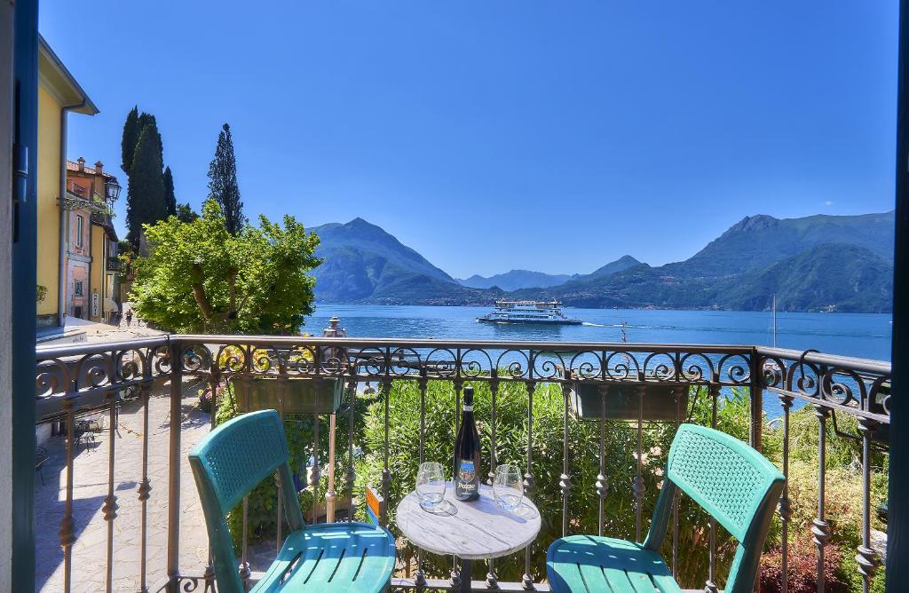 a table and chairs on a balcony with a view of the water at Casa Bella in Varenna