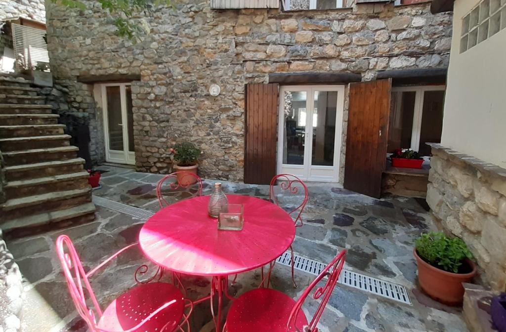 una mesa roja y sillas en un patio en Le Manaïrou, en Valdeblore