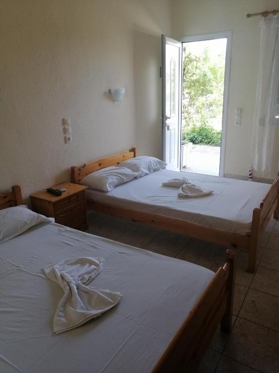 dwa łóżka w pokoju z oknem w obiekcie Apartments Christina w mieście Nea Vrasna