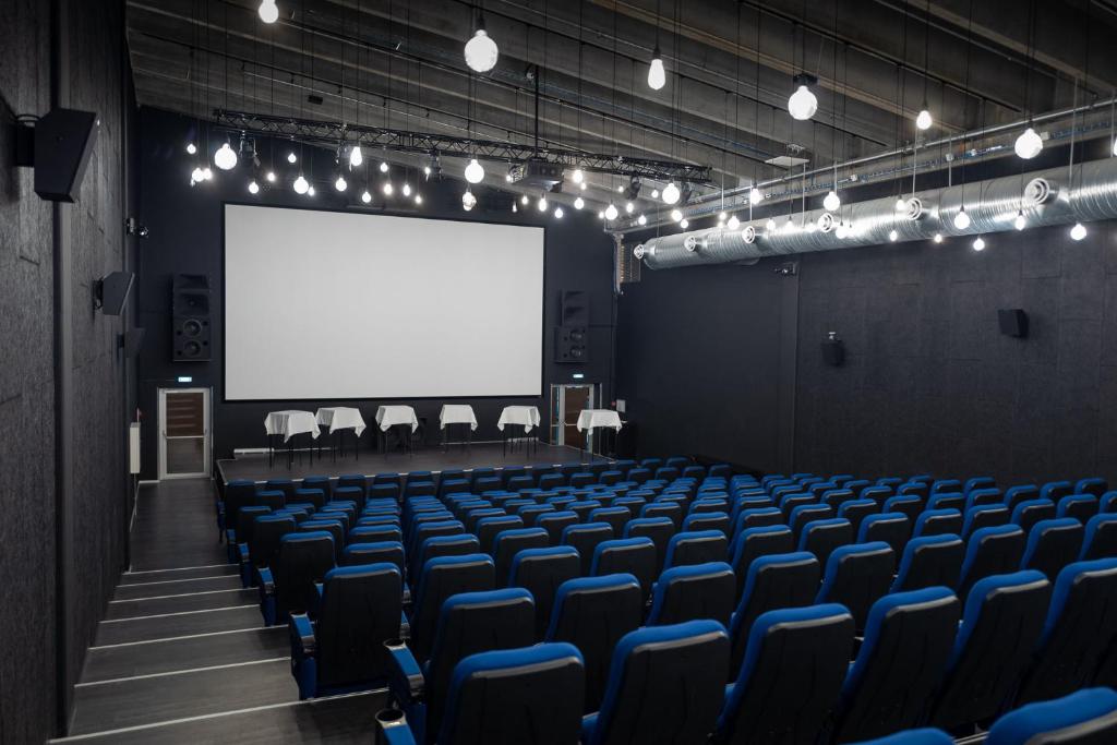 an empty auditorium with blue chairs and a white screen at Cabinn Copenhagen in Copenhagen