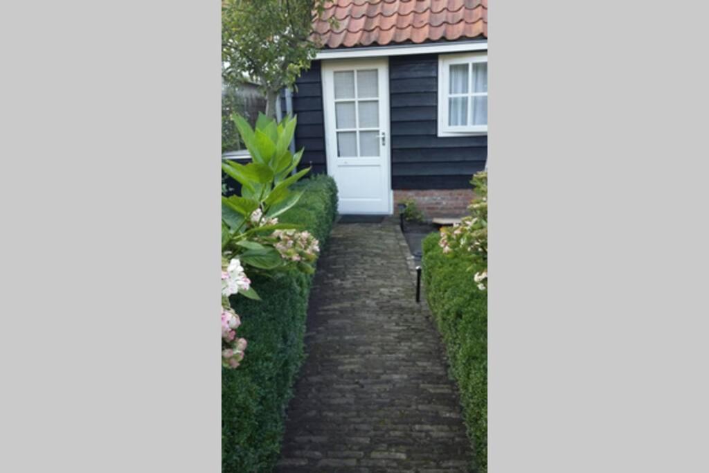 a brick path leading to a house with a white door at Omas kleine huisje in Veere