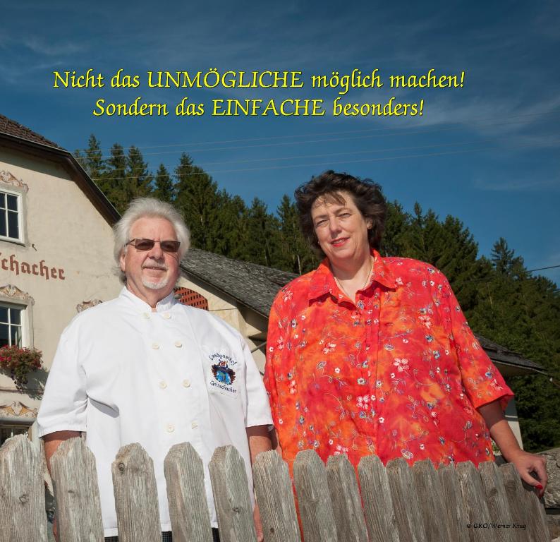 a man and a woman standing next to a fence at Landhaus Gritschacher in Sankt Peter in Holz
