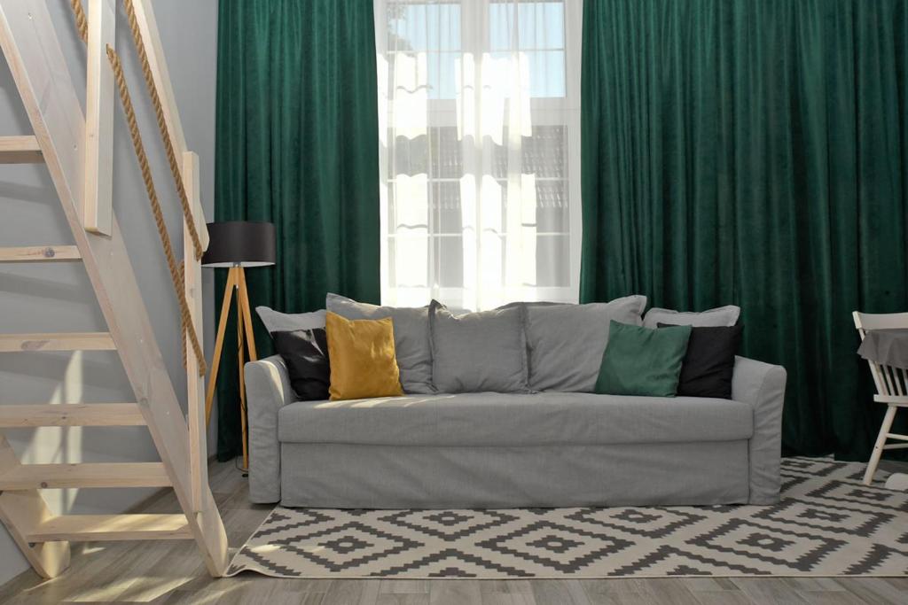 sala de estar con sofá y cortinas verdes en Przystań Twórców en Słupsk
