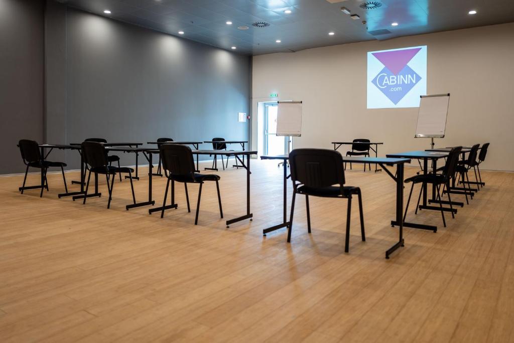 a conference room with tables and chairs and a screen at Cabinn Copenhagen in Copenhagen