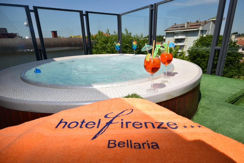 a hot tub on a balcony with two cocktails at Hotel Firenze in Bellaria-Igea Marina