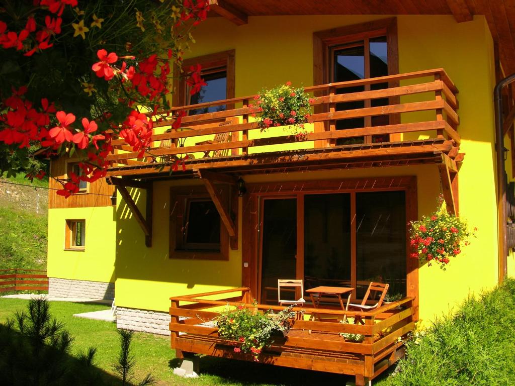 a yellow house with a deck with a table and chairs at Penzión Jozef a apartmány in Demanovska Dolina