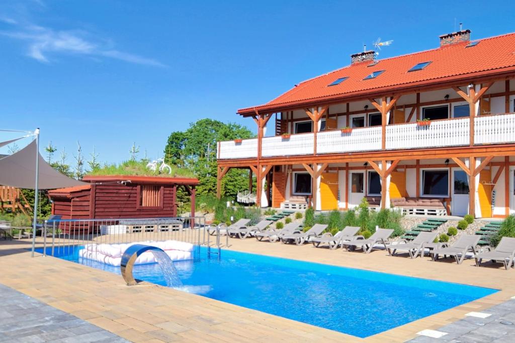 a resort with a swimming pool in front of a building at Złociste Zacisze in Dąbki