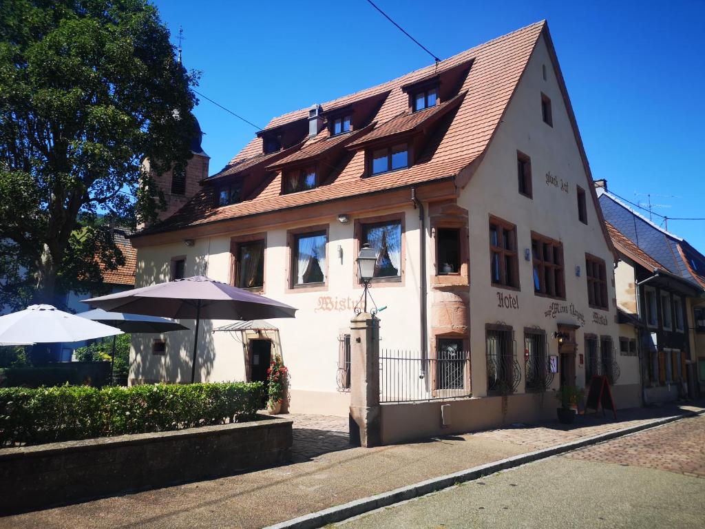 - un bâtiment blanc avec un parasol devant dans l'établissement Hotel Wistub Aux Mines d'Argents, à Sainte-Marie-aux-Mines