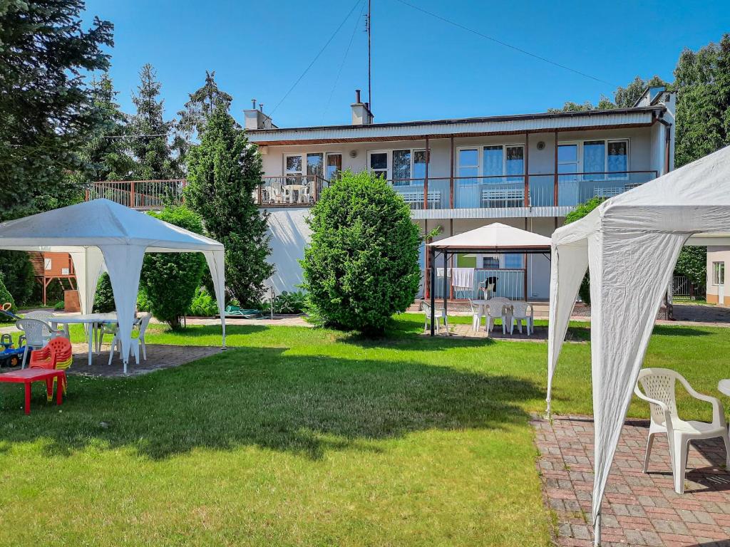 a yard with white tents and chairs and a building at Łodzianka in Mrzeżyno