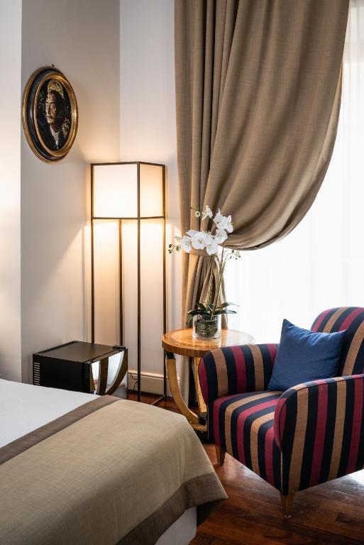 a bedroom with a bed and a chair and a lamp at AQA Palace in Florence