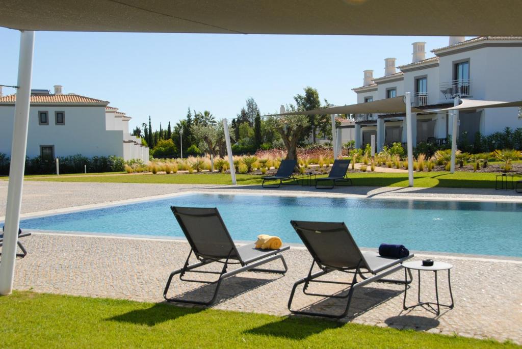 um par de cadeiras sentadas ao lado de uma piscina em Quinta do Algarvio Village em Carvoeiro