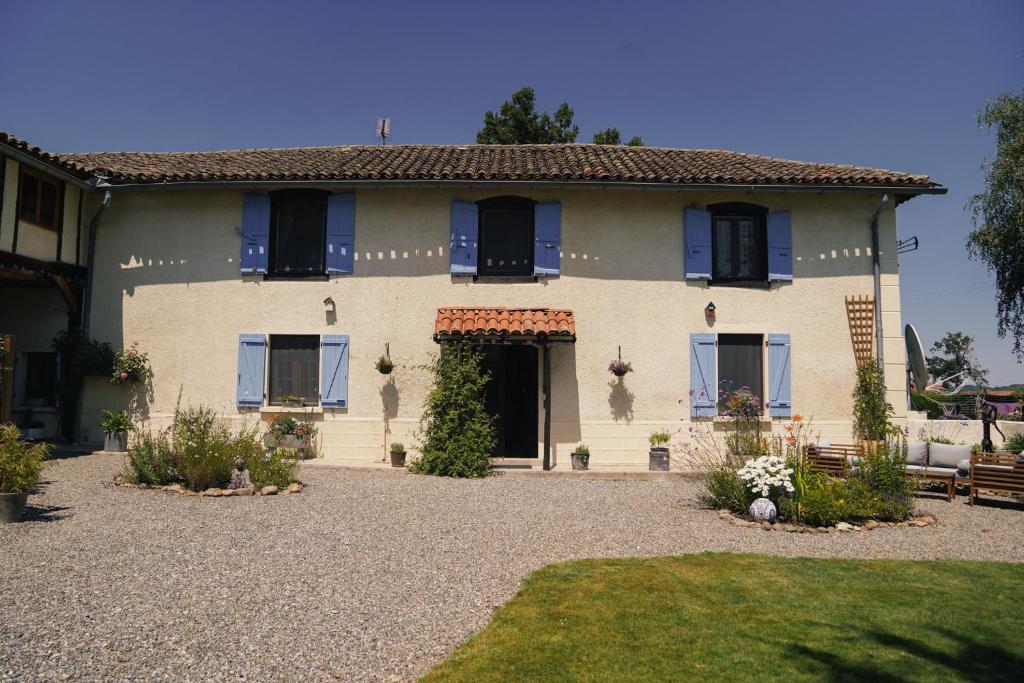 a large house with blue windows and a yard at Michouat Chambre D'Hotes in Vidou