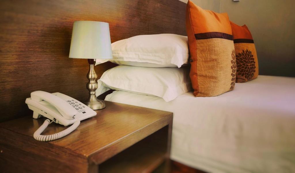 um telefone numa mesa ao lado de uma cama com almofadas em Stay Inn - Guest House em Maputo