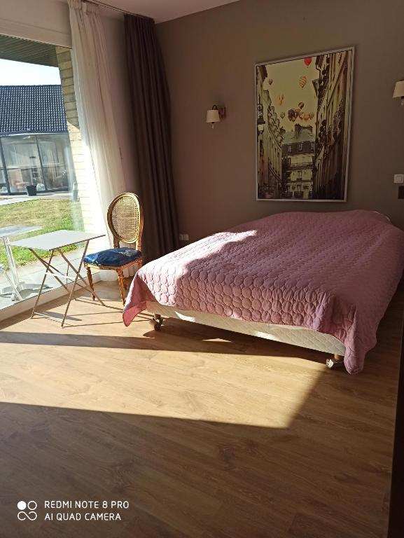 a bedroom with a bed and a table and a window at Hotel Fleur de Lys in Bailleul