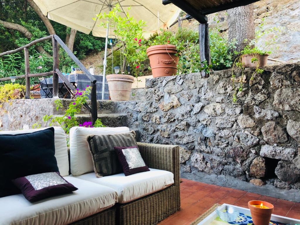 un divano su un patio con parete in pietra di Le Miniere Apartments a Monte Argentario