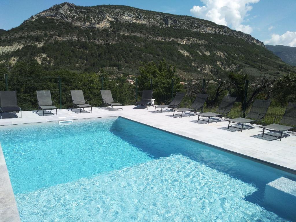 a swimming pool with chairs and a mountain in the background at Le Mas des Fontettes, gite 14 personnes, piscine chauffée, propriété 5ha, barbecue in Sahune