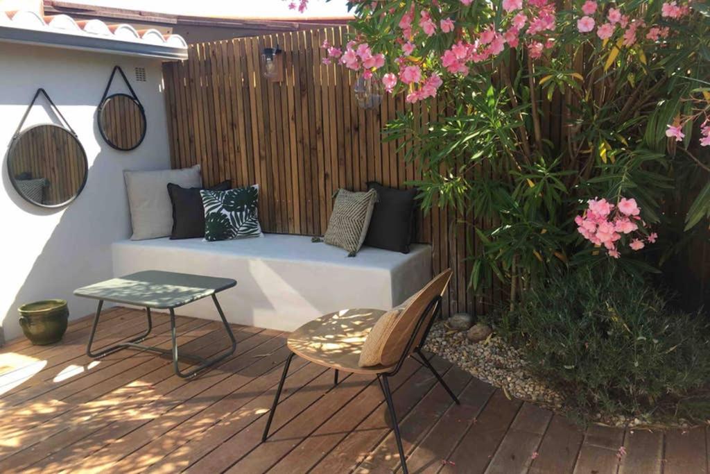 eine Terrasse mit einer Bank, einem Tisch und Blumen in der Unterkunft Villa bord de mer in Torreilles