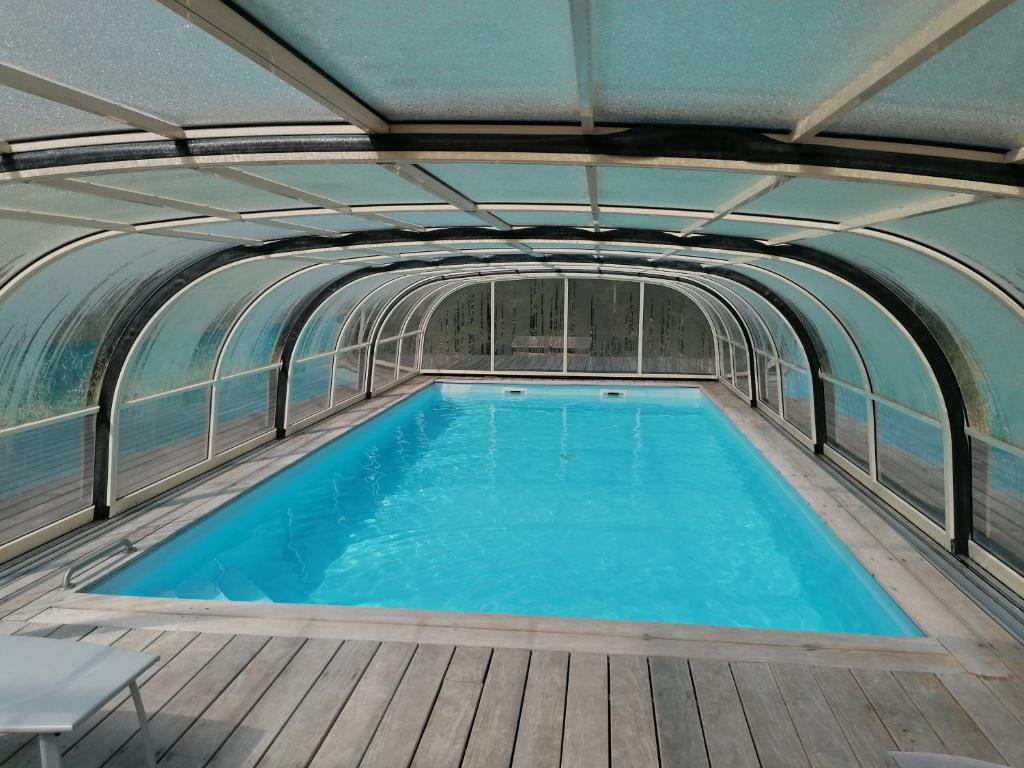 a swimming pool in a building with a ceiling at Belge'attitude Maison d'hôtes in Commequiers