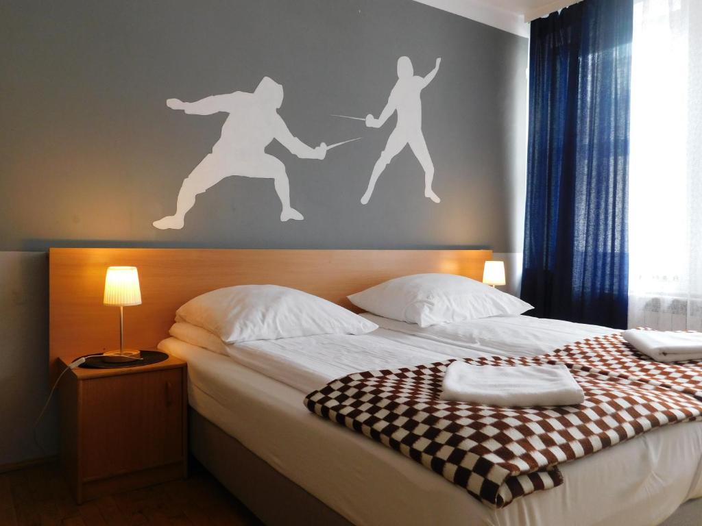 Un dormitorio con una cama con una pared con gente. en Pokoje Gościnne Korona en Cracovia