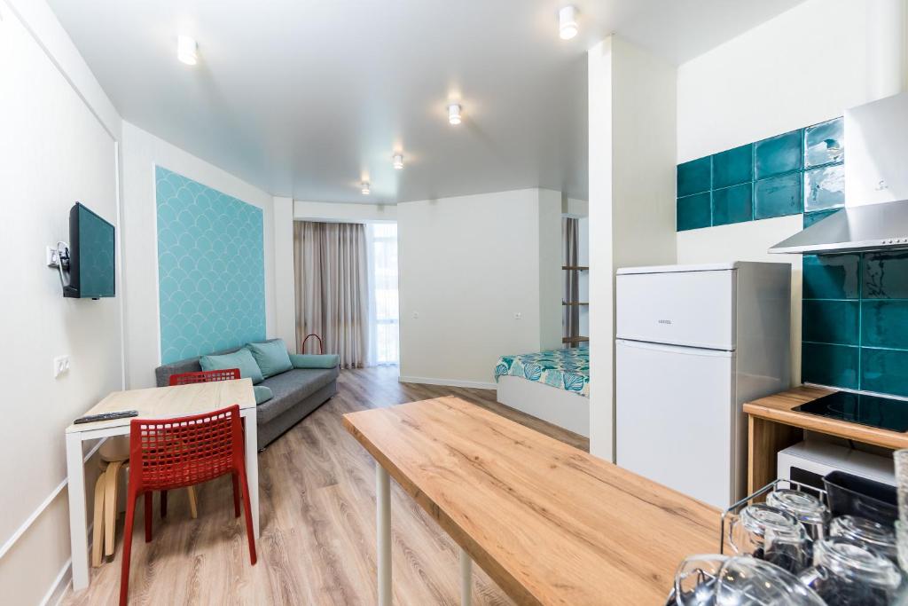 eine Küche und ein Wohnzimmer mit einem Tisch und einem Sofa in der Unterkunft Апартаменты "Гамма ДеЛюкс" in Olginka
