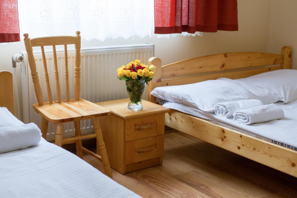 a bedroom with two beds and a chair and a vase of flowers at Hostel Rest in Krakow