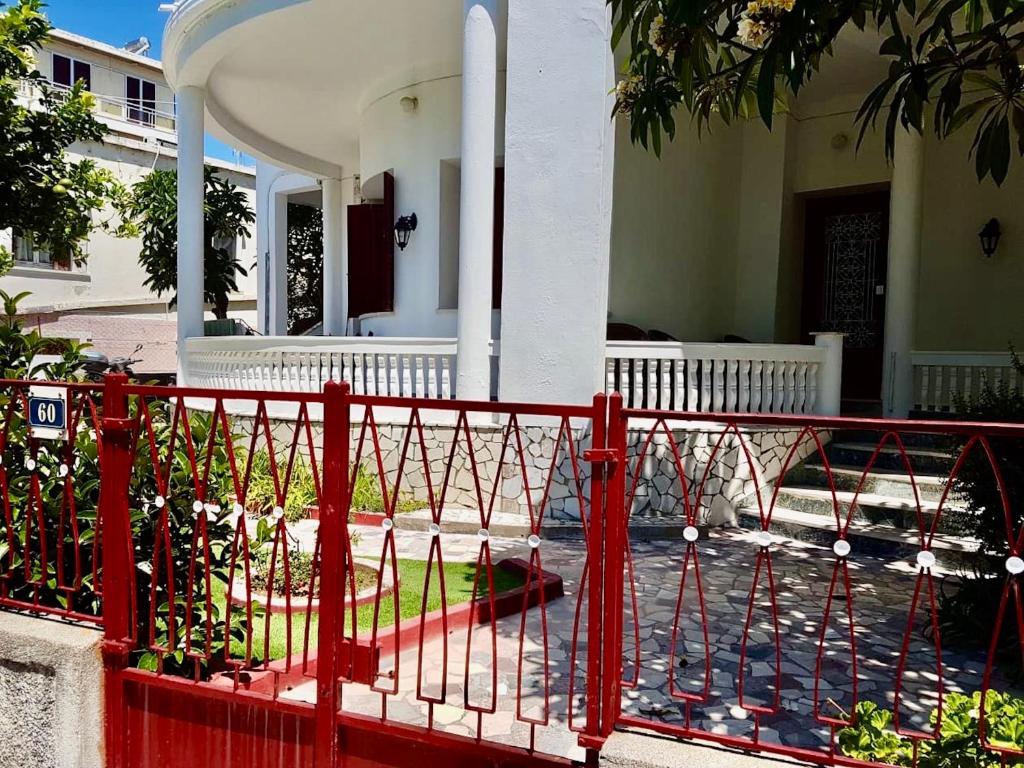 una cerca roja frente a una casa en The Metropolis Residence Rhodes en Rodas