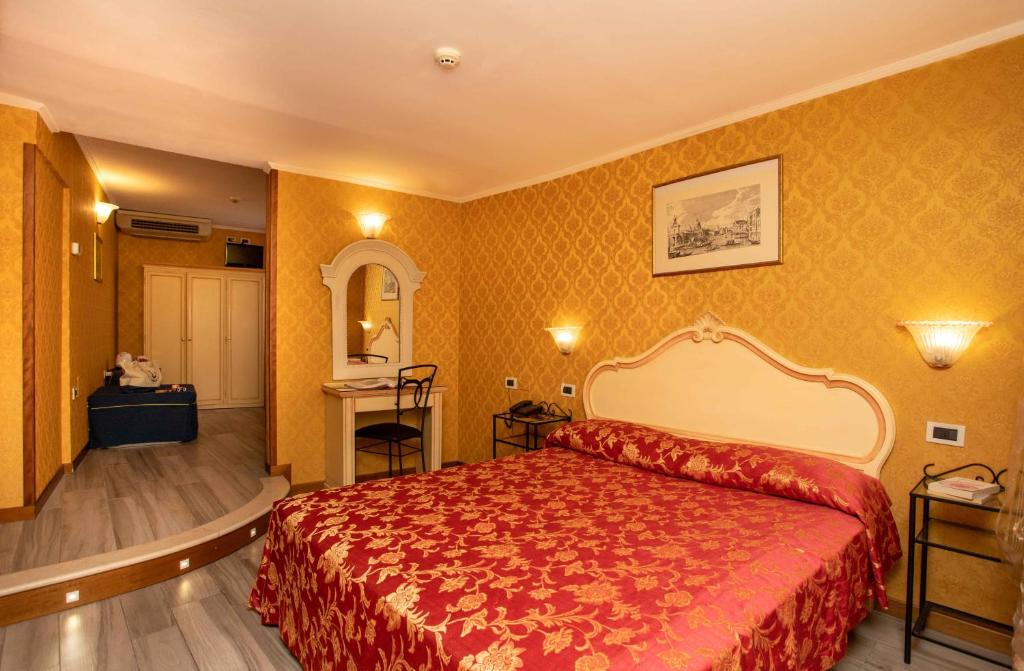 a hotel room with a red bed and yellow walls at Hotel Tintoretto in Venice