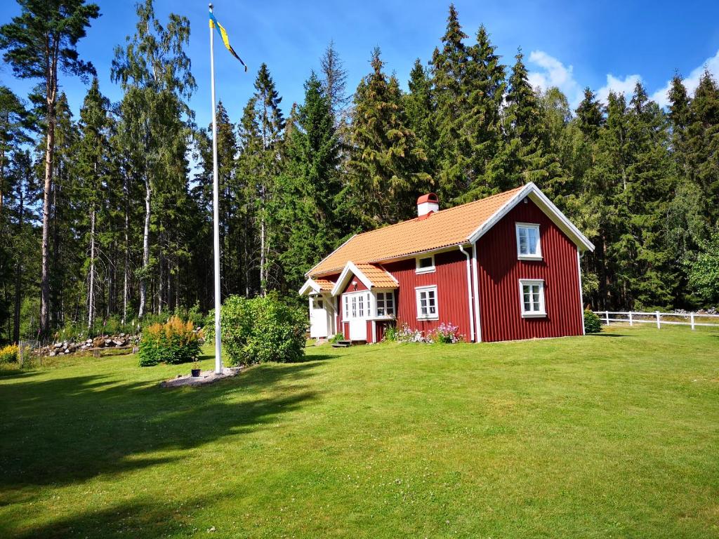 a red house on a green field with trees at Torpet Norra Lundåsen in Fristad