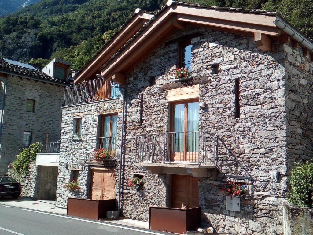 a stone building with a balcony on a street at merian in Piuro