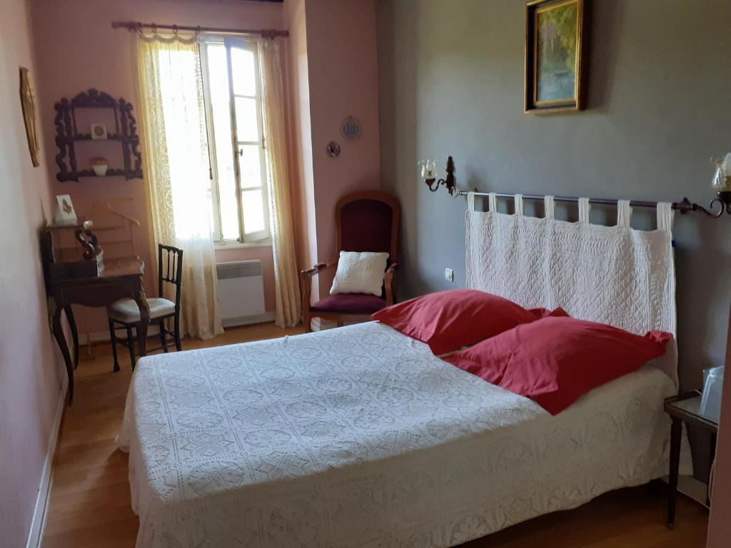 a bedroom with a white bed with red pillows at La Grange in Le Plan