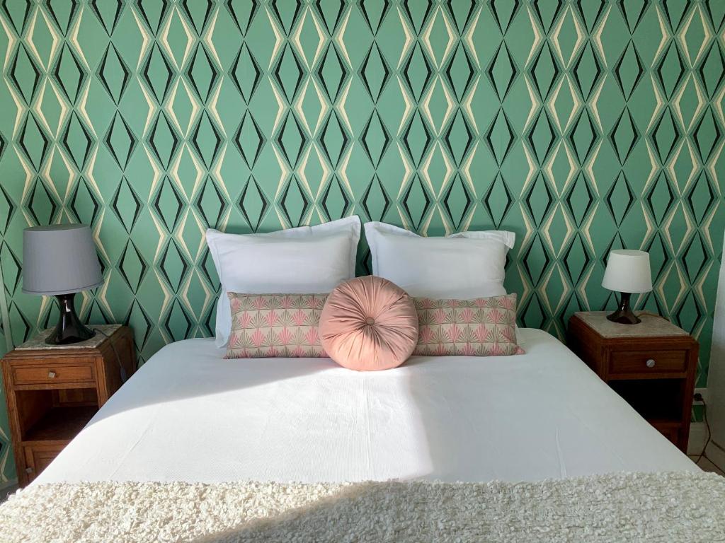ein Schlafzimmer mit einem Bett mit zwei Lampen und einer Wand in der Unterkunft La Villégiature in Vichy