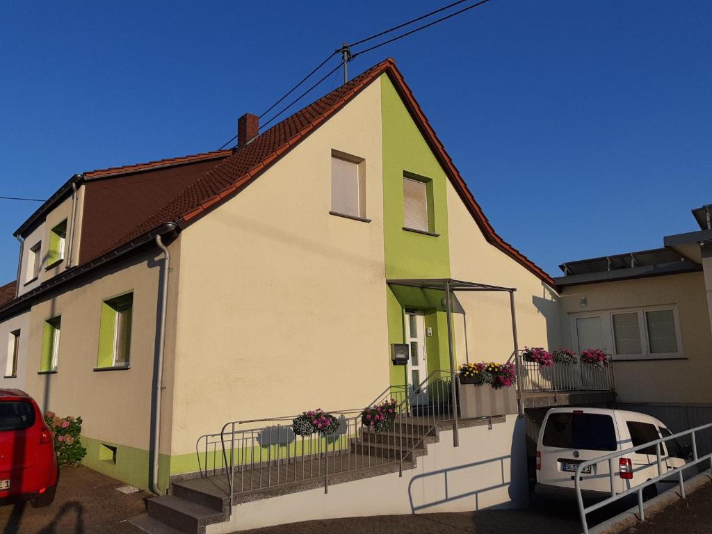 una casa blanca y verde con un coche aparcado al lado en Appartement Merl en Saarwellingen