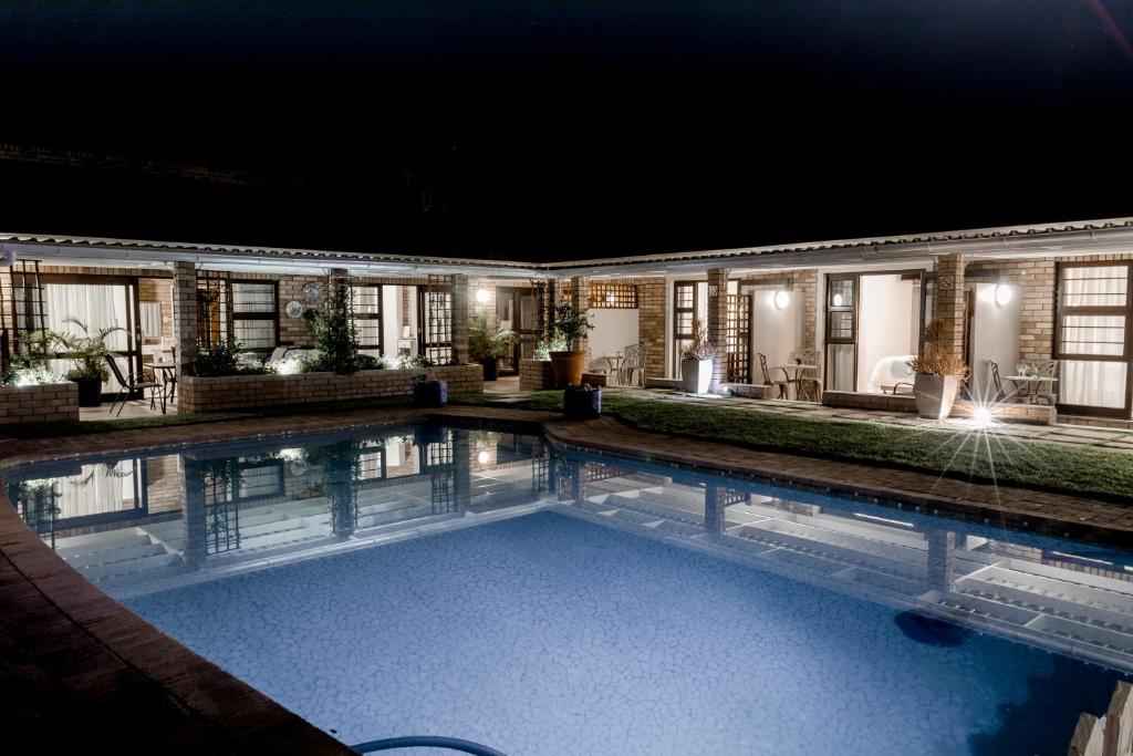 a swimming pool in front of a house at night at Wagtails Guest House in Port Elizabeth