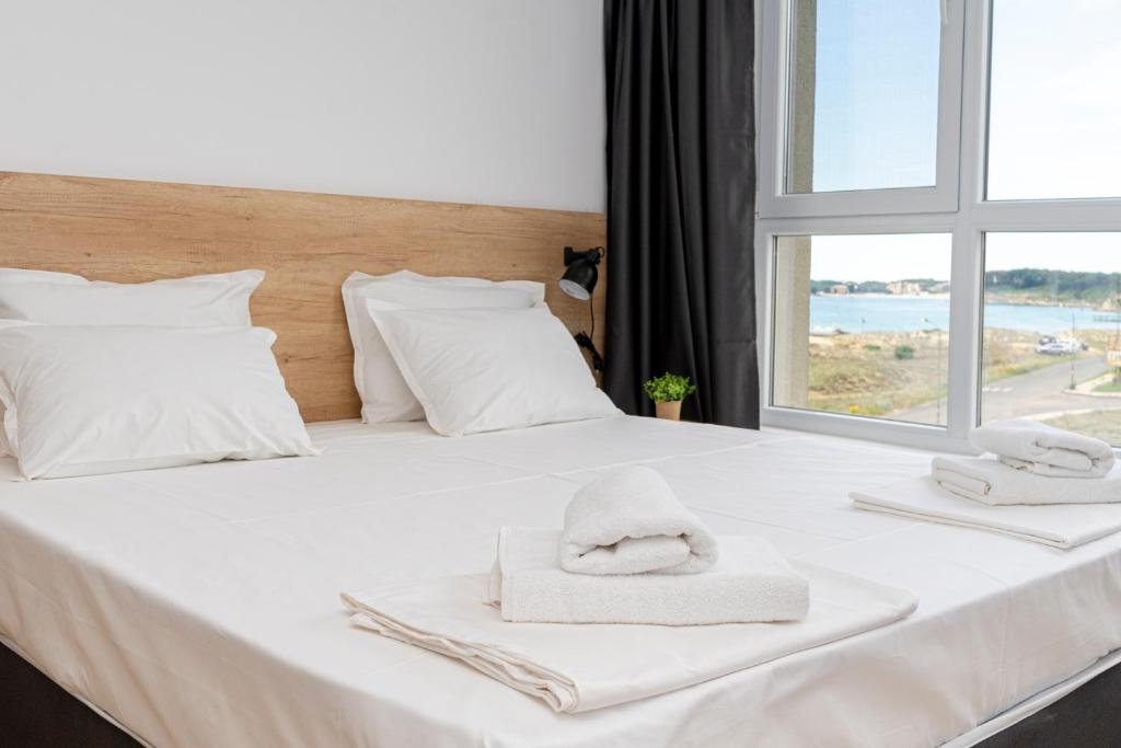 a white bed with towels on it with a window at Aparthotel Primorsko in Primorsko