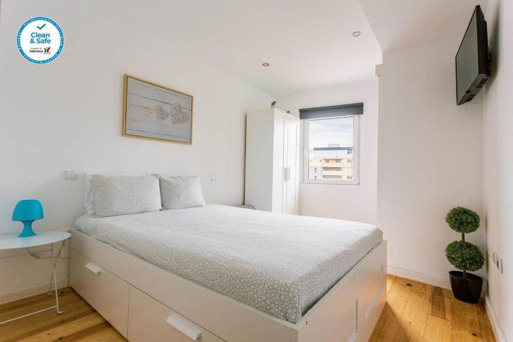 una camera da letto bianca con un letto e una televisione di PortoVivo Bonjardim Apartamento a Porto