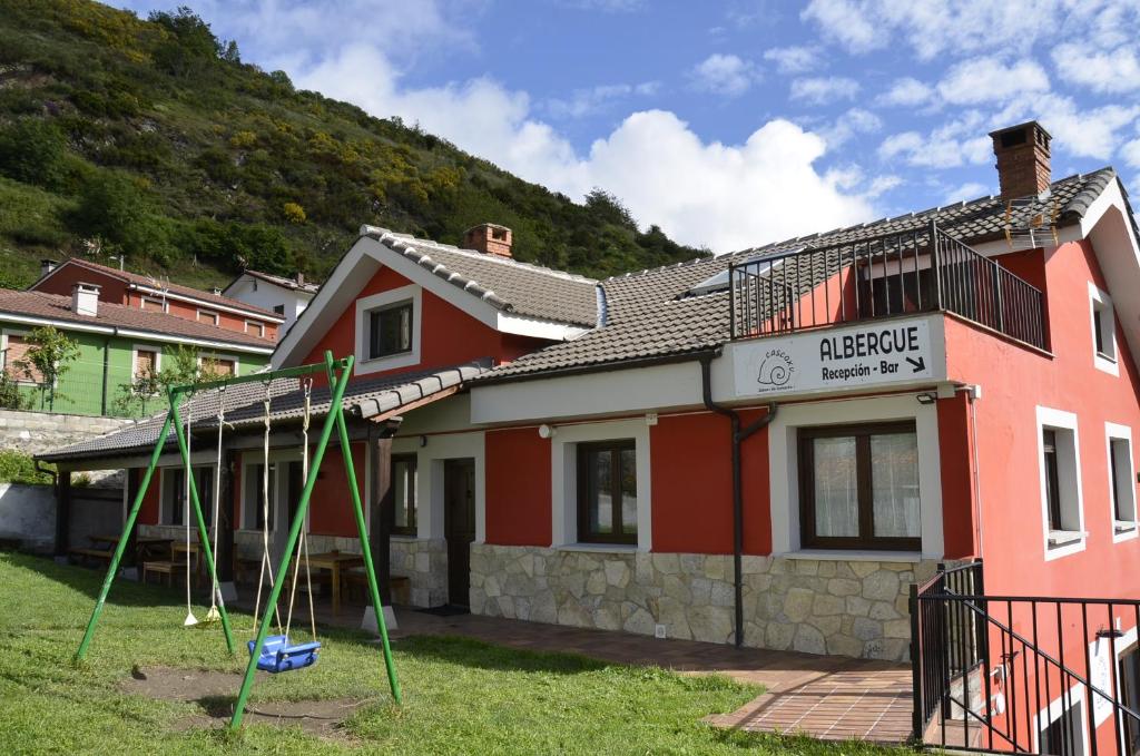 uma casa com um parque infantil em frente em Albergue Cascoxu 