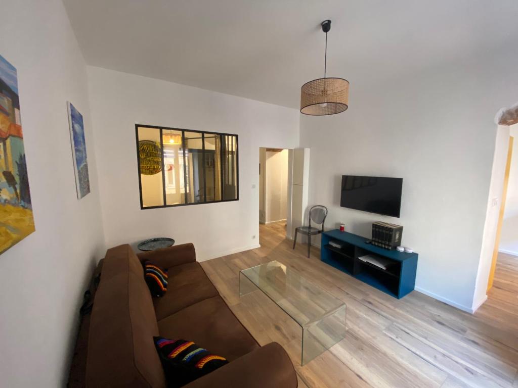 ein Wohnzimmer mit einem braunen Sofa und einem TV in der Unterkunft Grand studio rue piétonne Ajaccio in Ajaccio