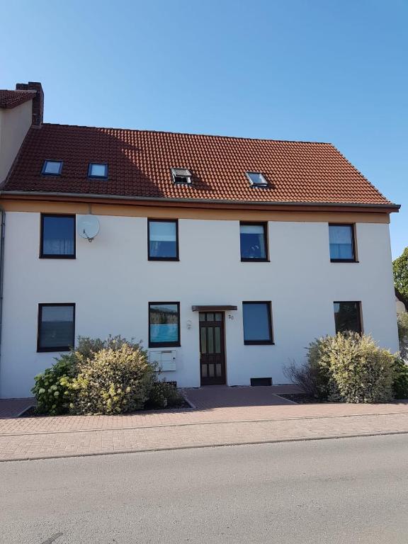 a white house with a red roof at Ferienwohnung am Kiessee in Breitungen