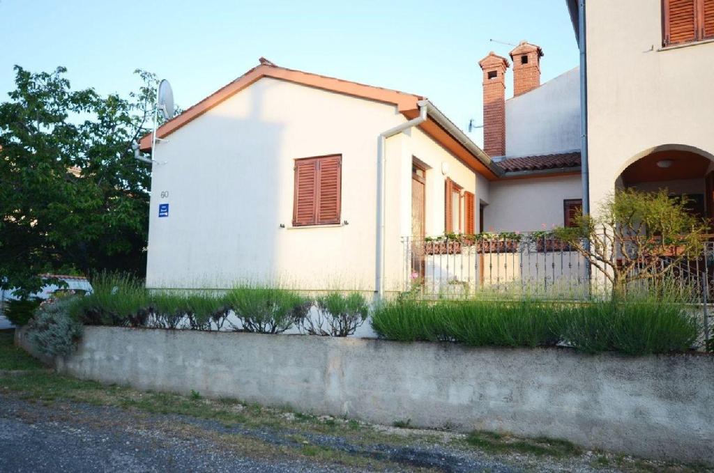 uma casa branca com uma cerca à frente. em Apartment Ljiljana em Fažana