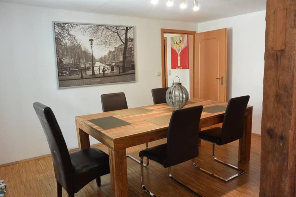 uma sala de jantar com uma mesa de madeira e cadeiras pretas em Direkt im Herzen von Bayreuth Wohnung S9 mit 115qm und großem Balkon em Bayreuth