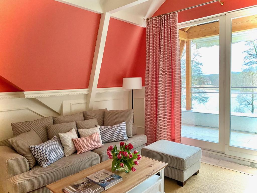 ein Wohnzimmer mit roten Wänden, einem Sofa und einem Tisch in der Unterkunft Ferienwohnung Carlotta in der Villa Seeblick in Bad Saarow