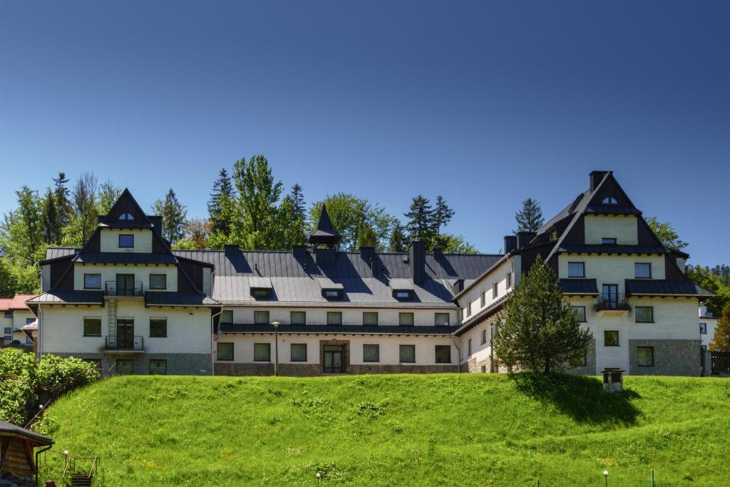 ein großes Haus auf einem Hügel mit grünem Gras in der Unterkunft Geovita Wisła in Wisła