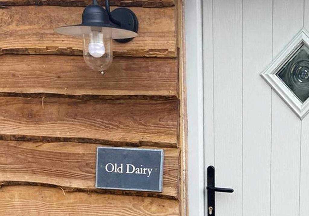 an old dairy sign on a wooden door with a lamp at Rowley Farm Holidays in Worcester