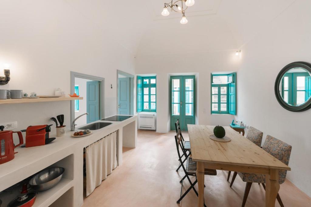 una cucina e una sala da pranzo con tavolo in legno di Santorinio Yellow House a Éxo Goniá